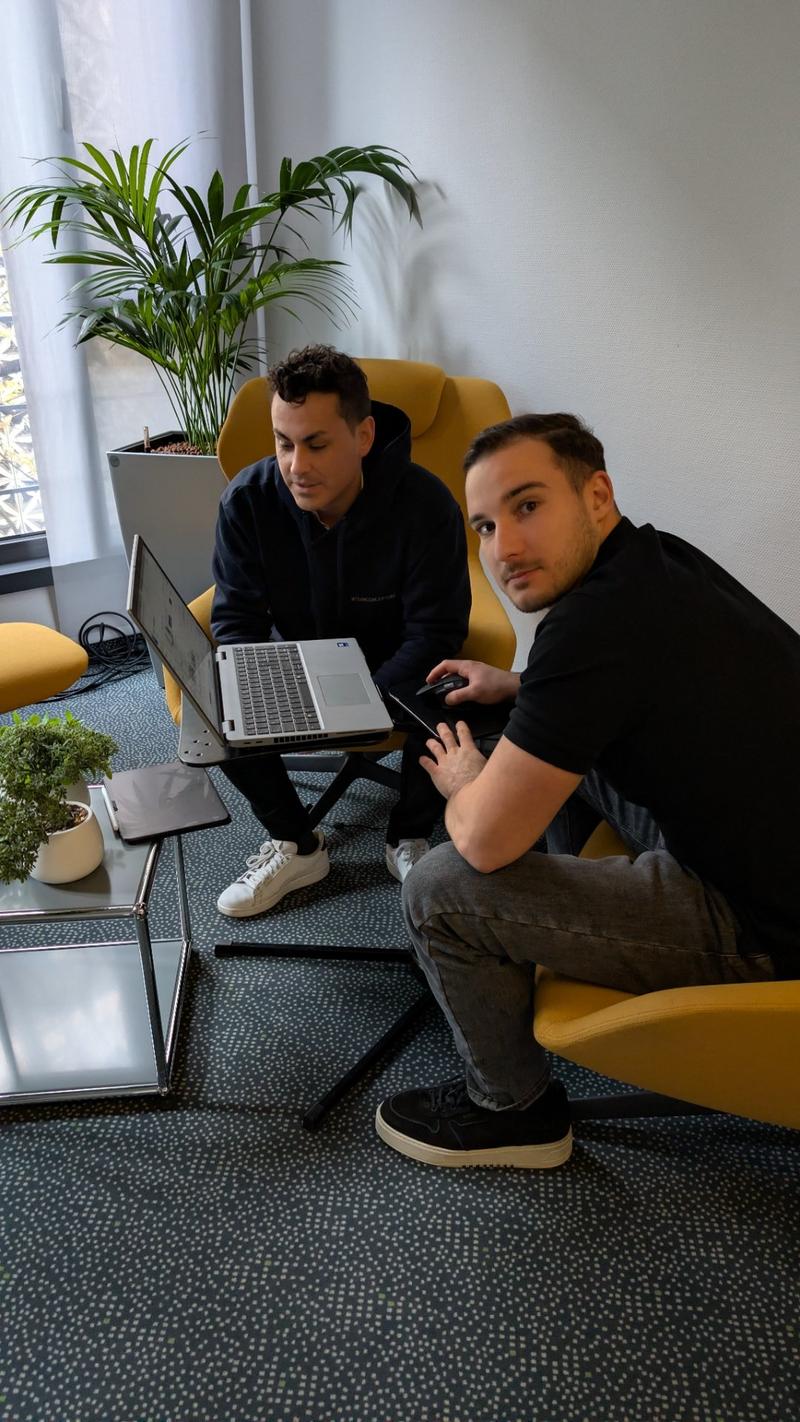 Two colleagues working together on a laptop in the office lounge