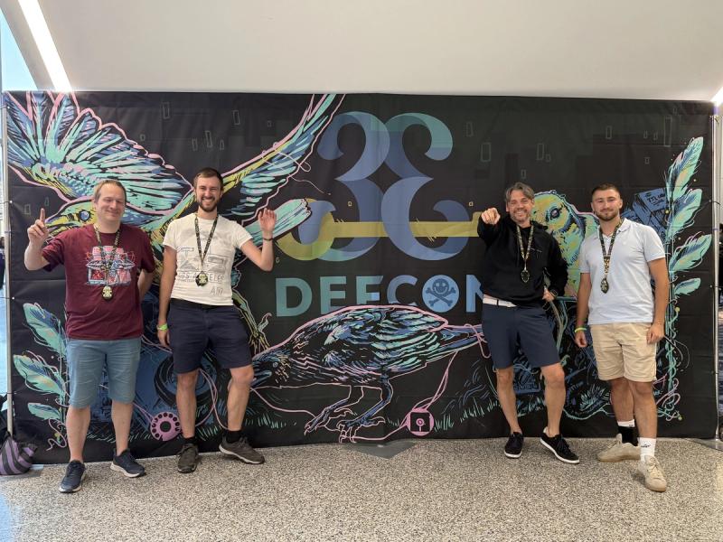 Team vor der DEF CON Wand auf der Security-Konferenz