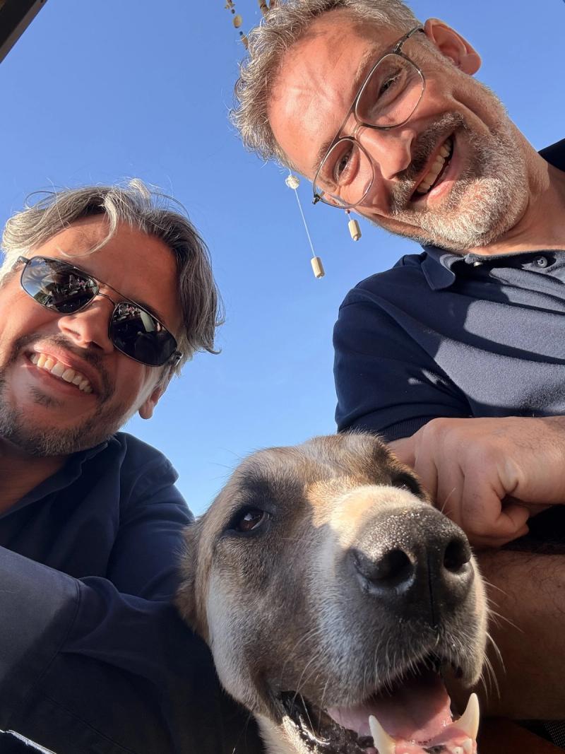 Zwei Kollegen machen ein Selfie mit einem Hund