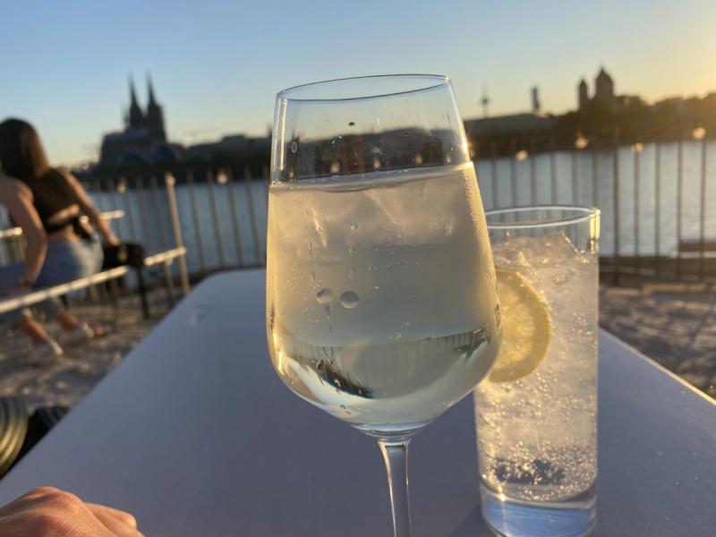 Weinglas bei Sonnenuntergang am Rhein mit Blick auf Koeln