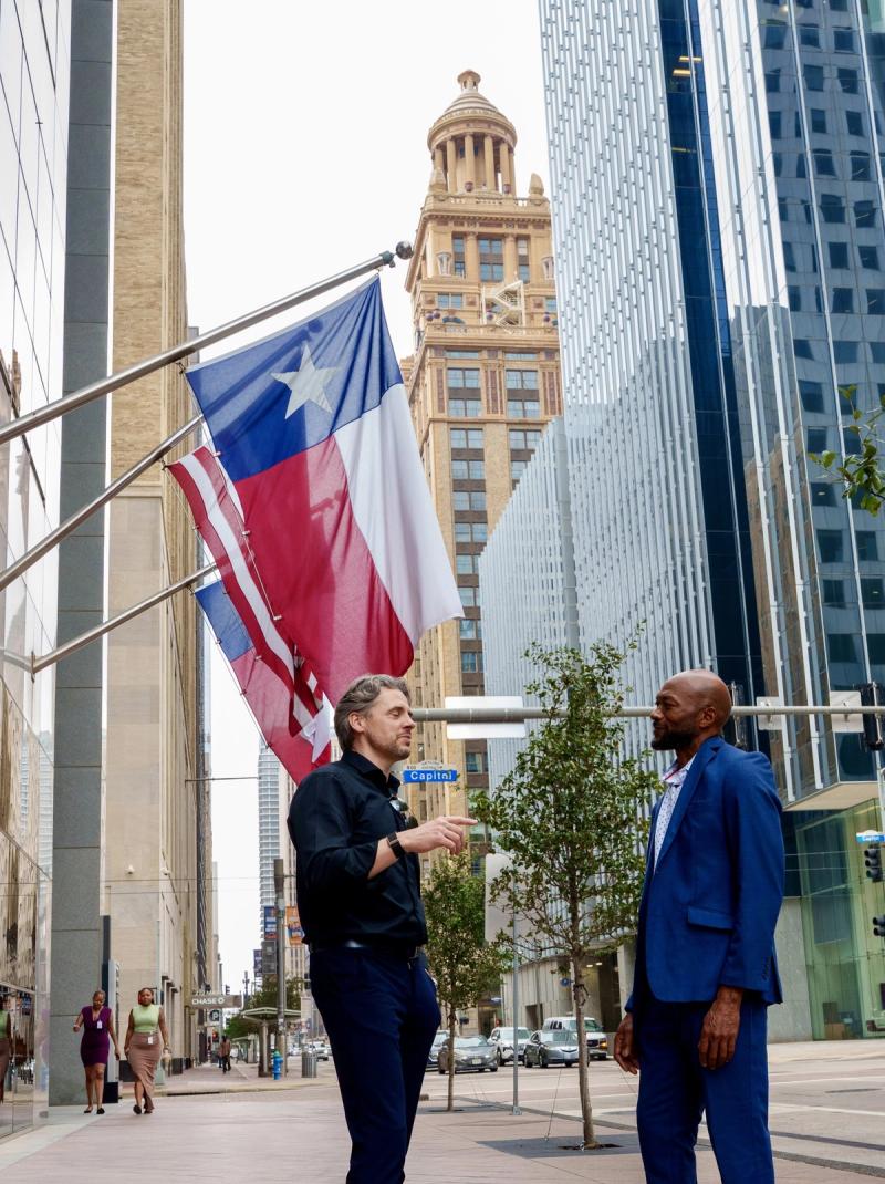 Zwei Kollegen im Gespraech vor der Texas-Flagge