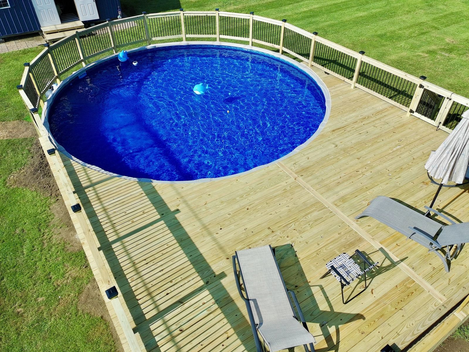 Custom pressure-treated deck built around above-ground pool in Camby with safety railing