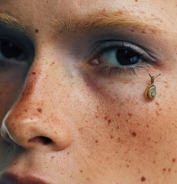 Tiny snail on a freckled face
