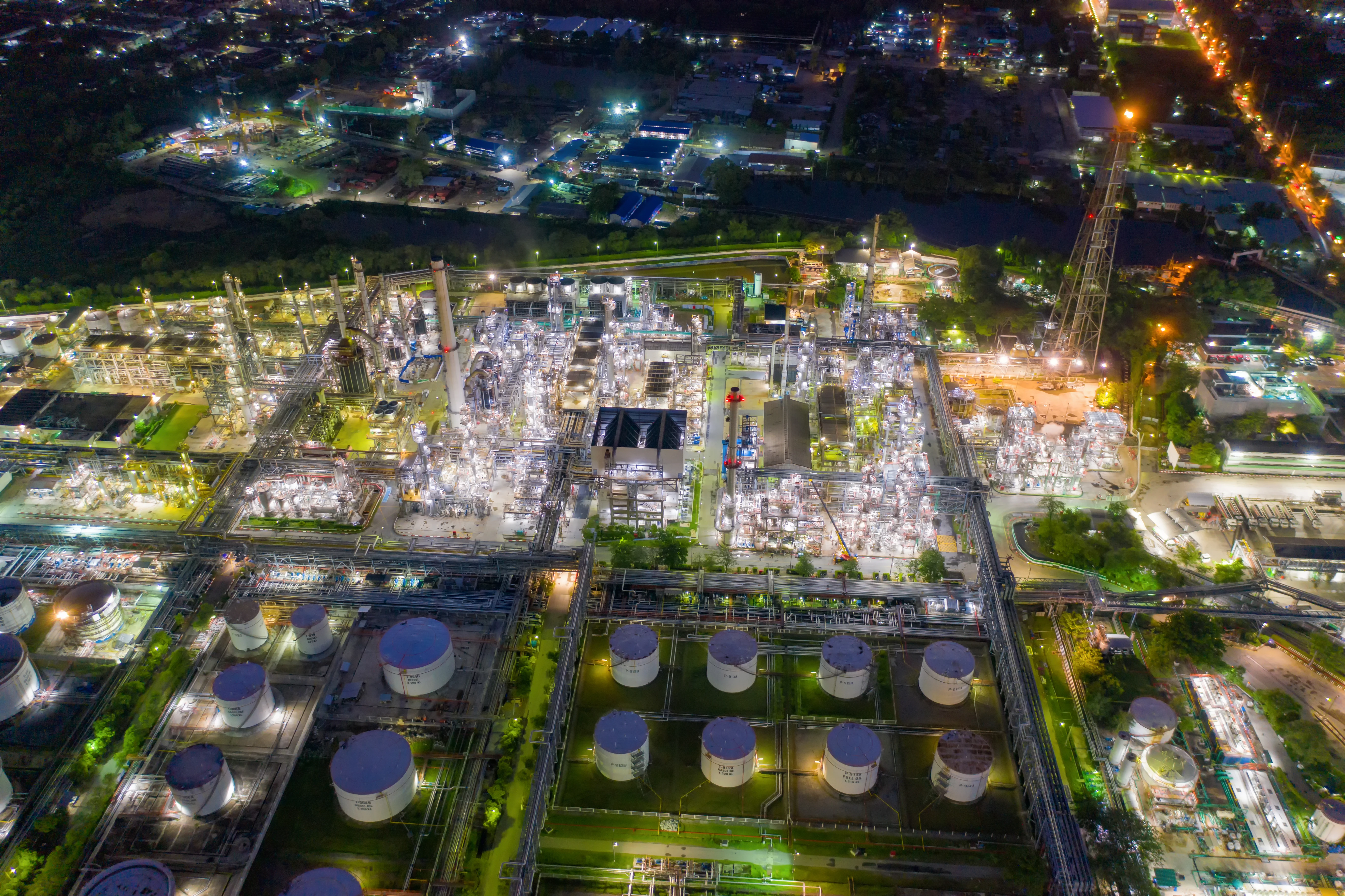 aerial view of oil refinery storage tanks at night lit up