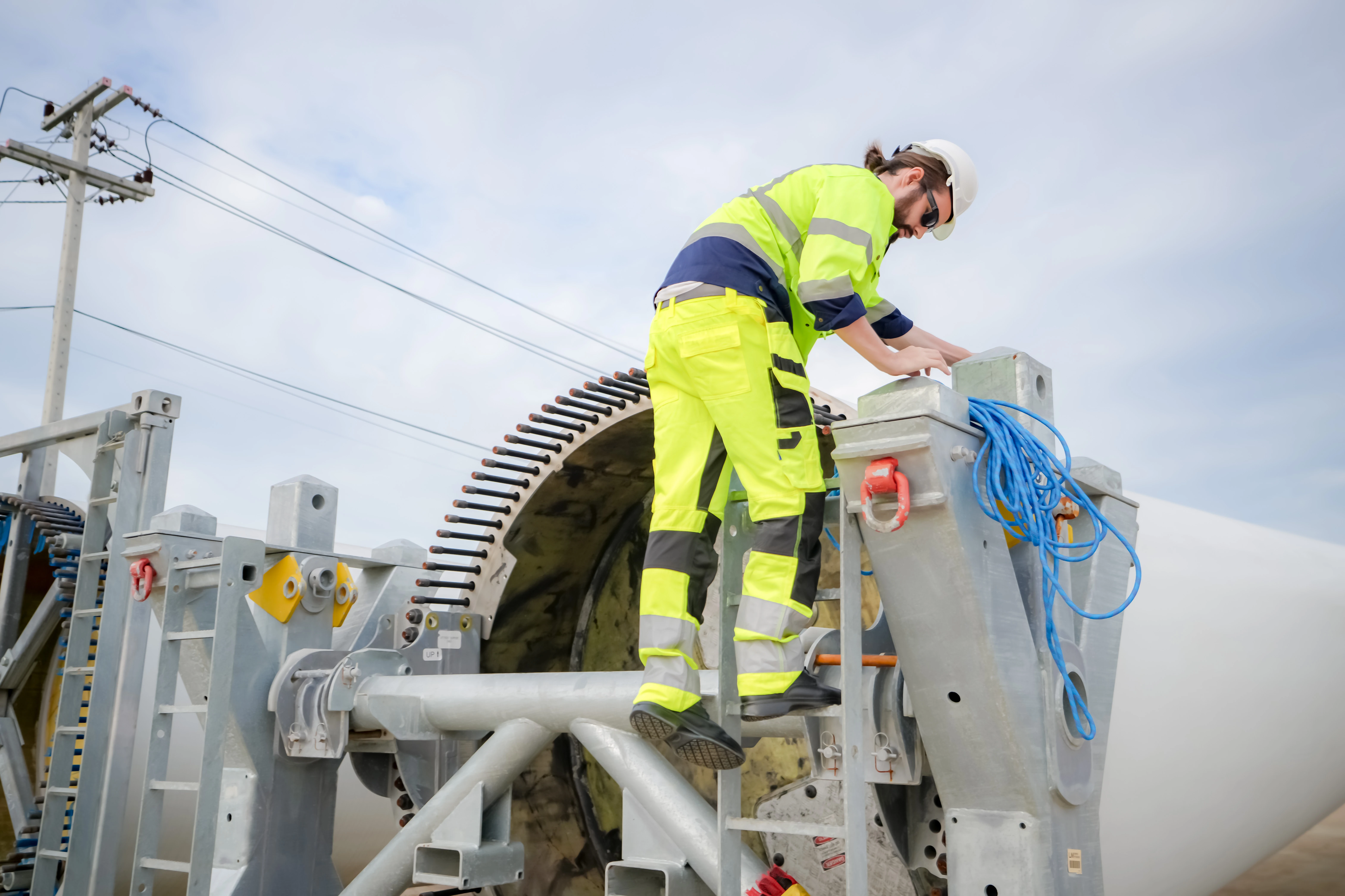 worker wearing PPE on wind turbine with bolts