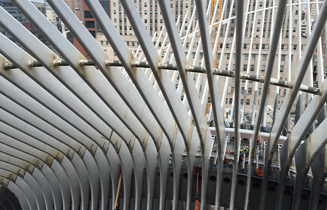A view of the steel ribs from several feet high, with two construction workers visible between the beams.