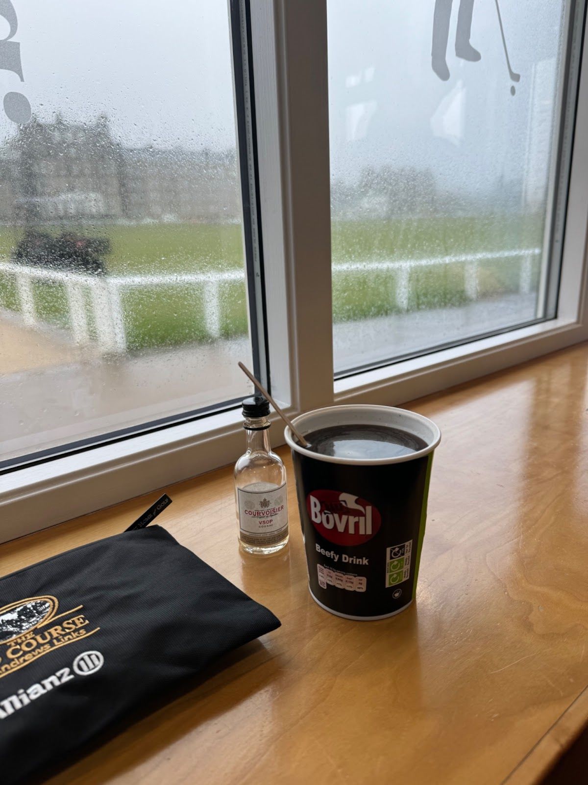 A cup of Bovril sits in front of a rainy window.