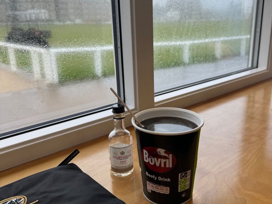 A cup of Bovril sits in front of a rainy window.