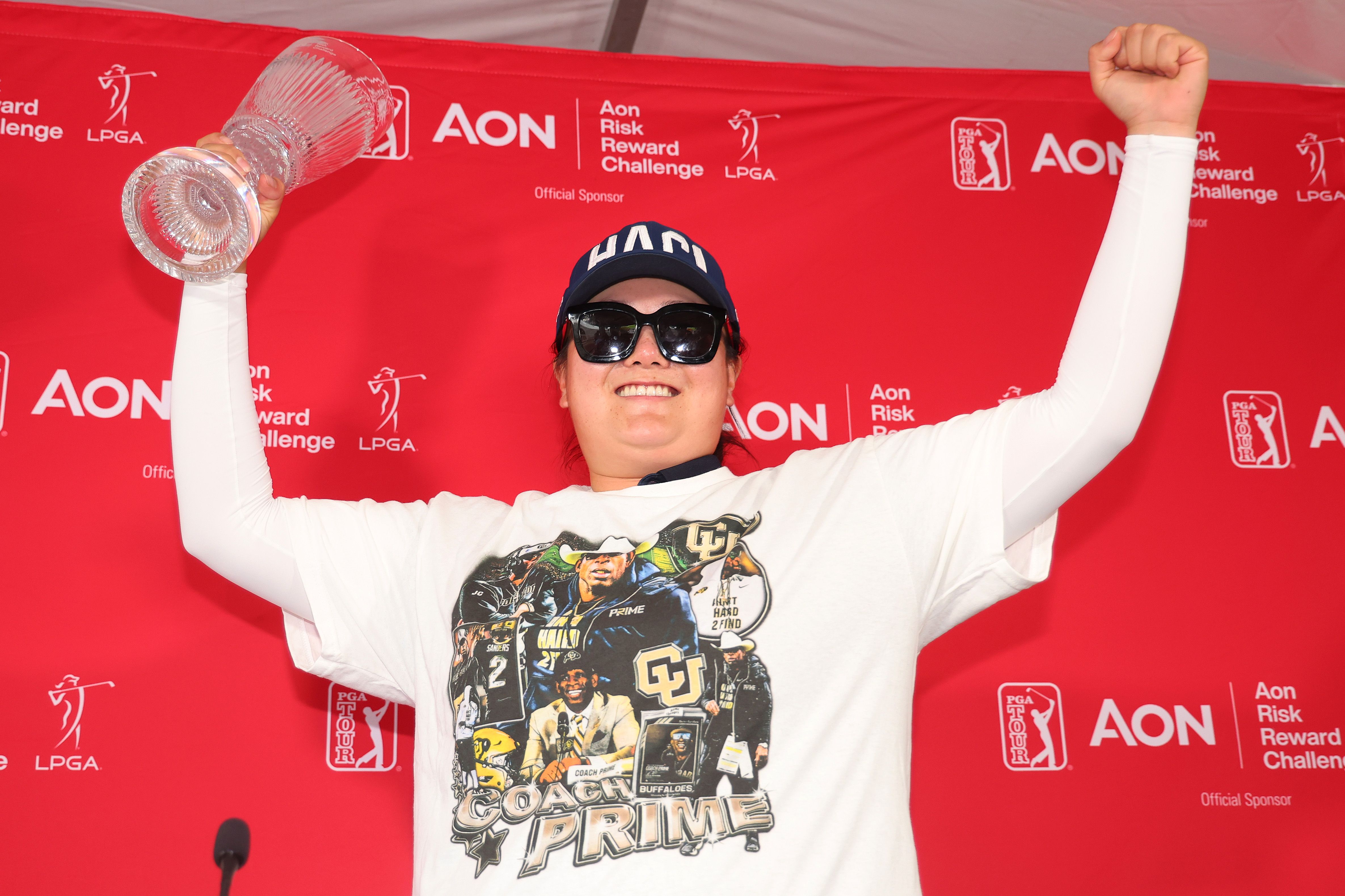 Angel Yin, donned in a Deion Sanders shirt and sunglasses, cheers after winning the 2023 Aon Risk Reward Challenge.