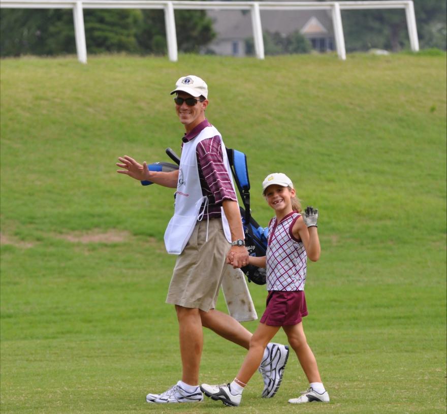 Young Rachel Heck hold her dad's hand, smiling and waving