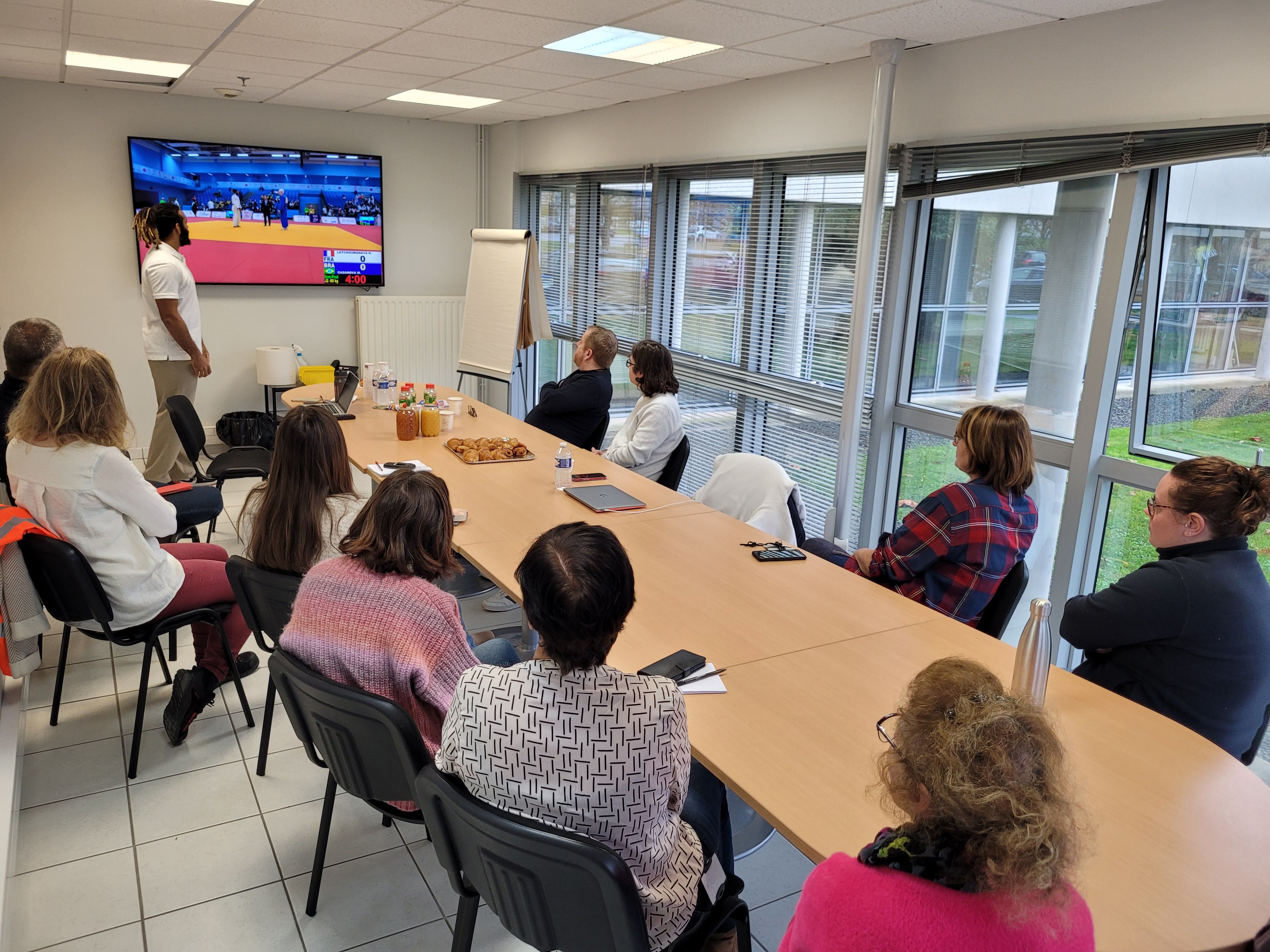 L'athlète Hélios présentant son parcours aux collaborateurs de Seifel assis autour d'une table