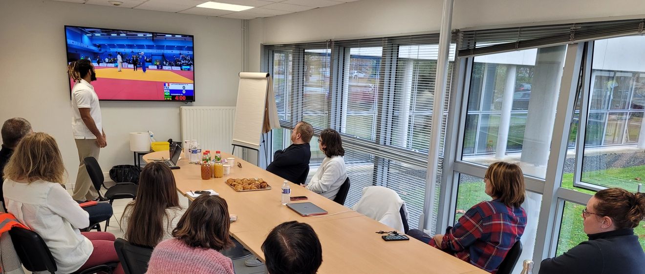 L'athlète Hélios présentant son parcours aux collaborateurs de Seifel assis autour d'une table