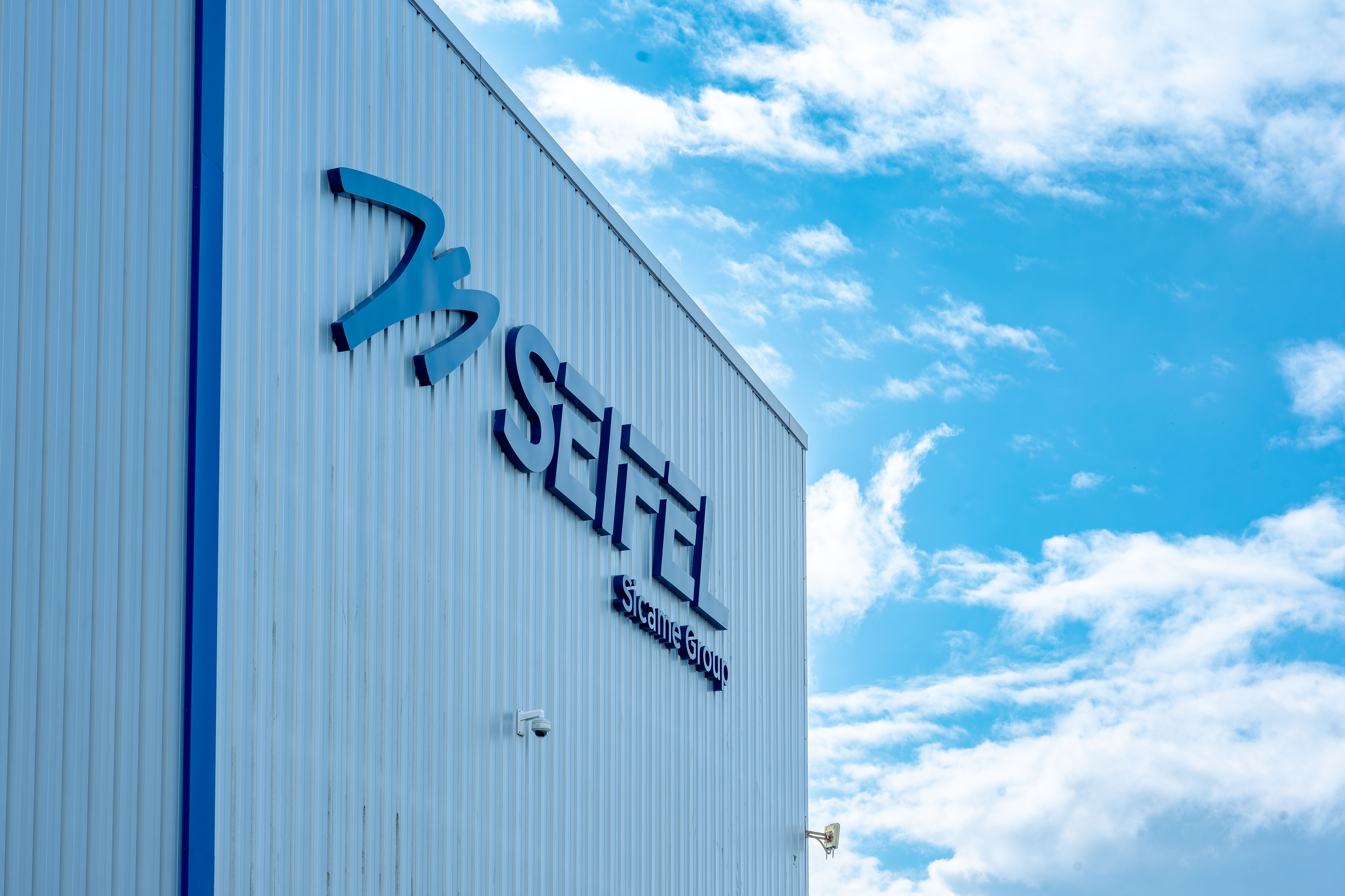 Logo de Seifel sur la façade de l'usine avec un ciel bleu et quelques nuages