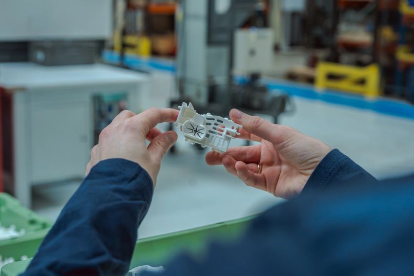 Mains d’un technicien tenant une petite pièce blanche