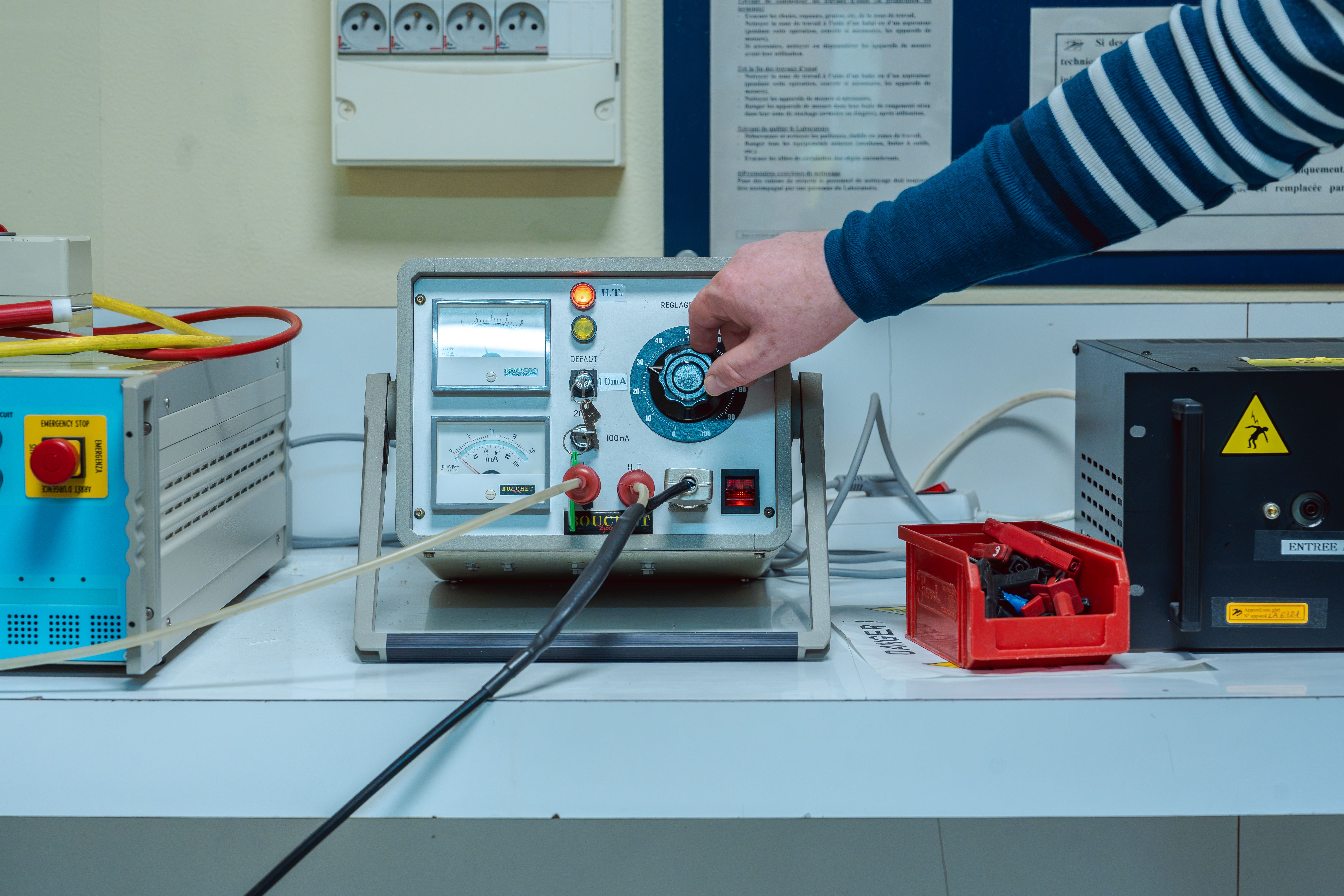 Main tournant un bouton de réglage sur une machine pour des tests électriques