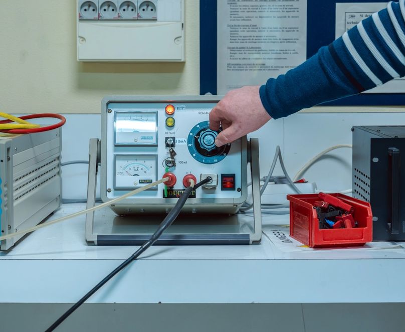 Main tournant un bouton de réglage sur une machine pour des tests électriques