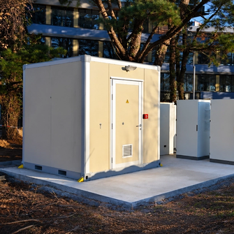 Shelter sur une plateforme en béton avec d'autres coffrets électriques et entouré d'arbres
