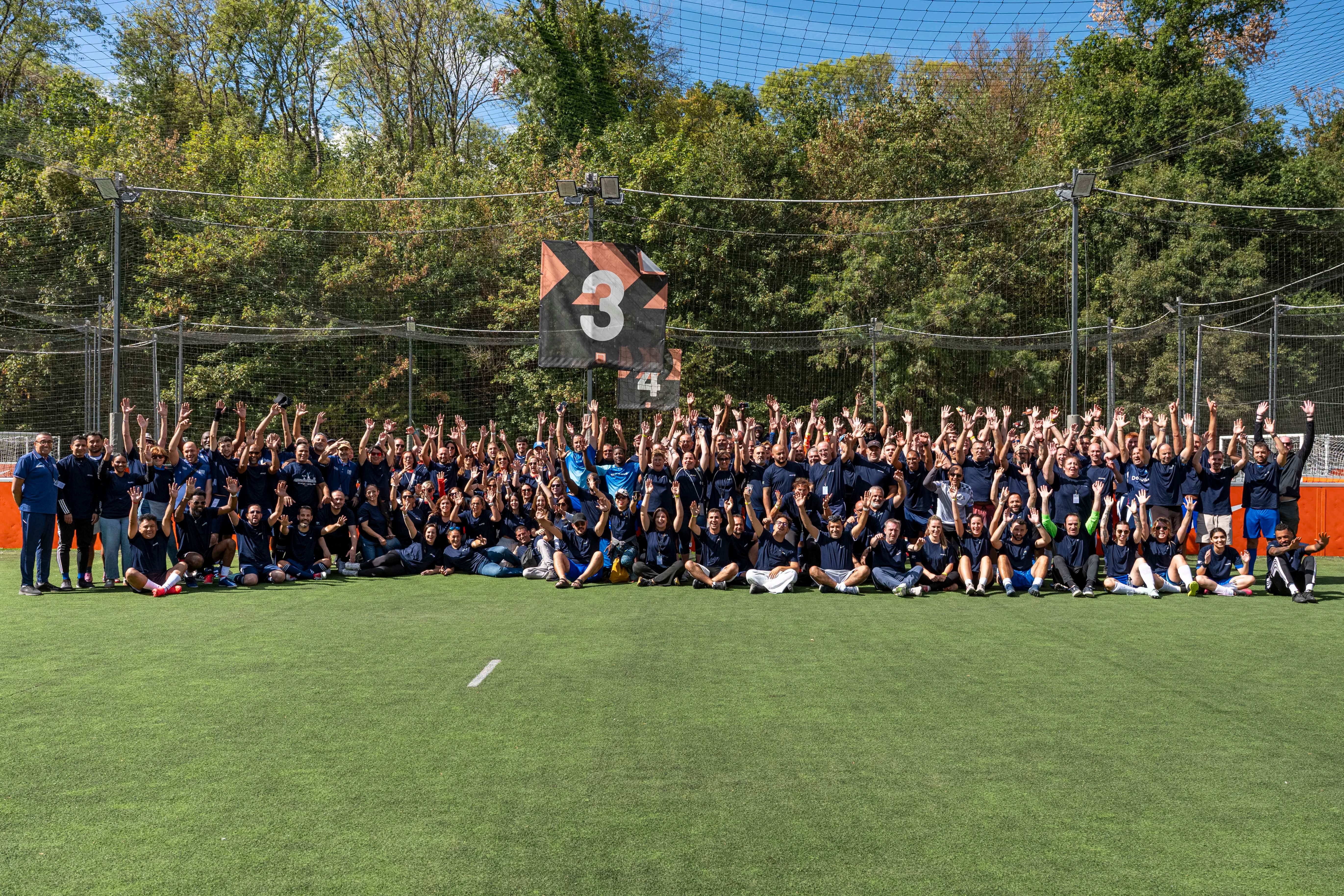 L'ensemble du groupe participant au tournoi sur un terrain et les bras en l'air