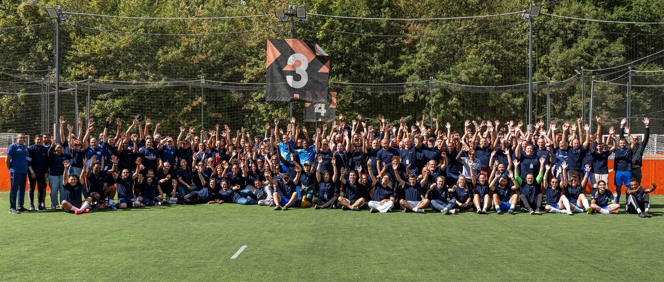 L'ensemble du groupe participant au tournoi sur un terrain et les bras en l'air