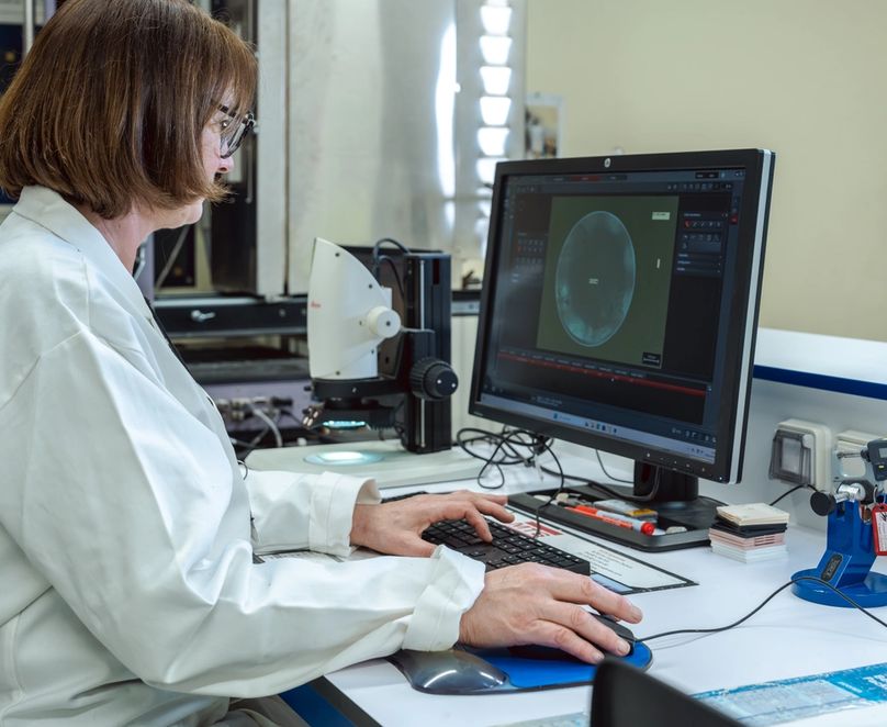 Technicienne assise devant un ordinateur du laboratoire avec des tests à l’écran