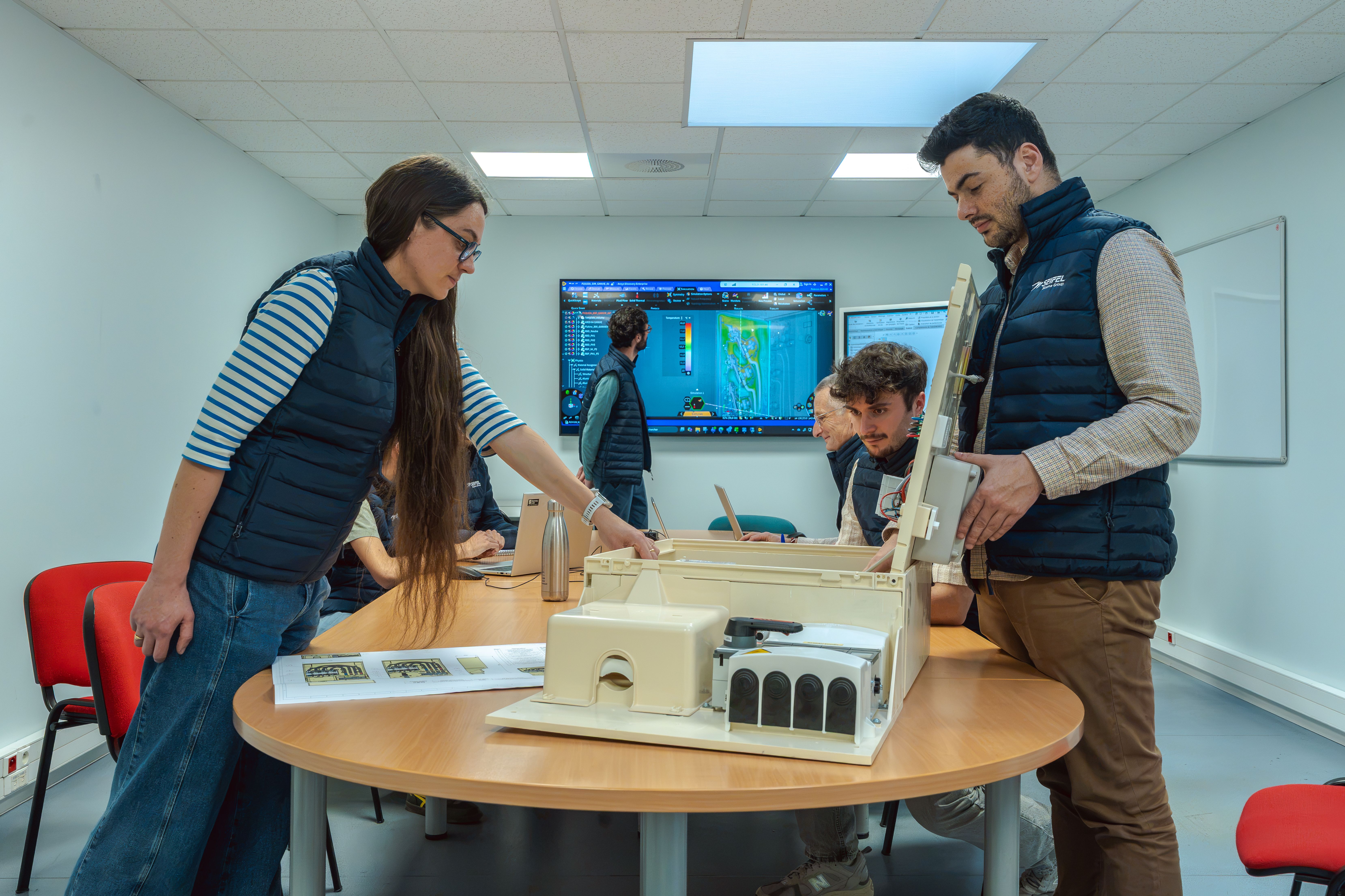Equipes R&D réunies dans une salle autour d’une table avec un abri coffret électrique