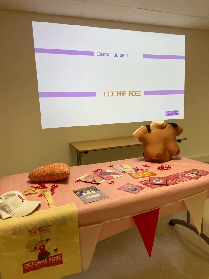 Table sur laquelle sont posés des flyers, des rubans roses et le buste