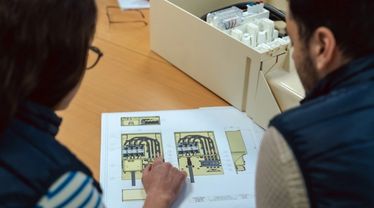 Deux personnes penchées sur une feuille avec un schéma d’un coffret électrique