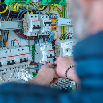 Mains d'un homme travaillant sur l'intérieur d'un coffret électrique