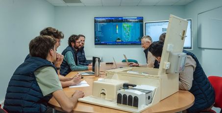 Equipes R&D réunies dans une salle autour d’une table avec un coffret électrique ouvert