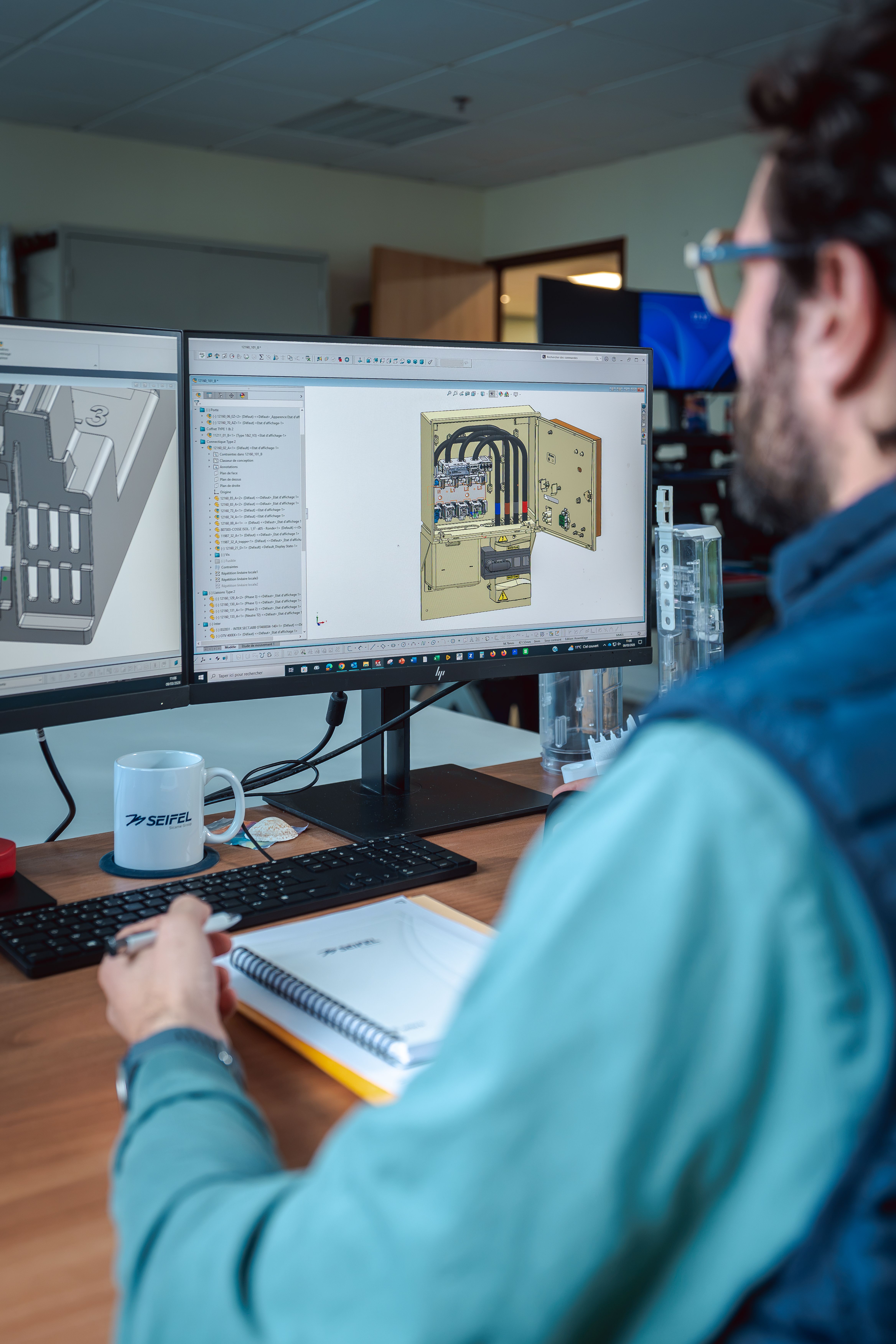 Homme devant un ordinateur affichant une modélisation 3D d’un coffret technique