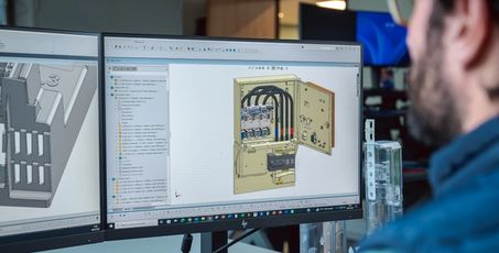 Homme devant un ordinateur affichant une modélisation 3D d’un coffret technique