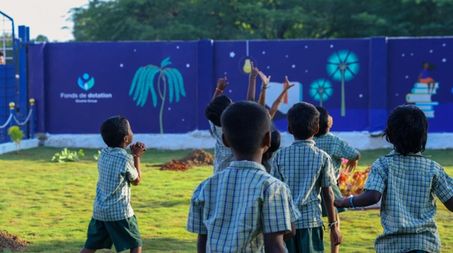Écoliers de dos marchant vers un mur avec le logo du Fonds de dotation en Inde