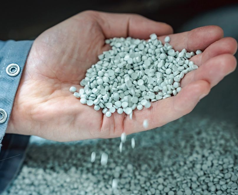 Main remplie de matière première sous forme de granulés blancs