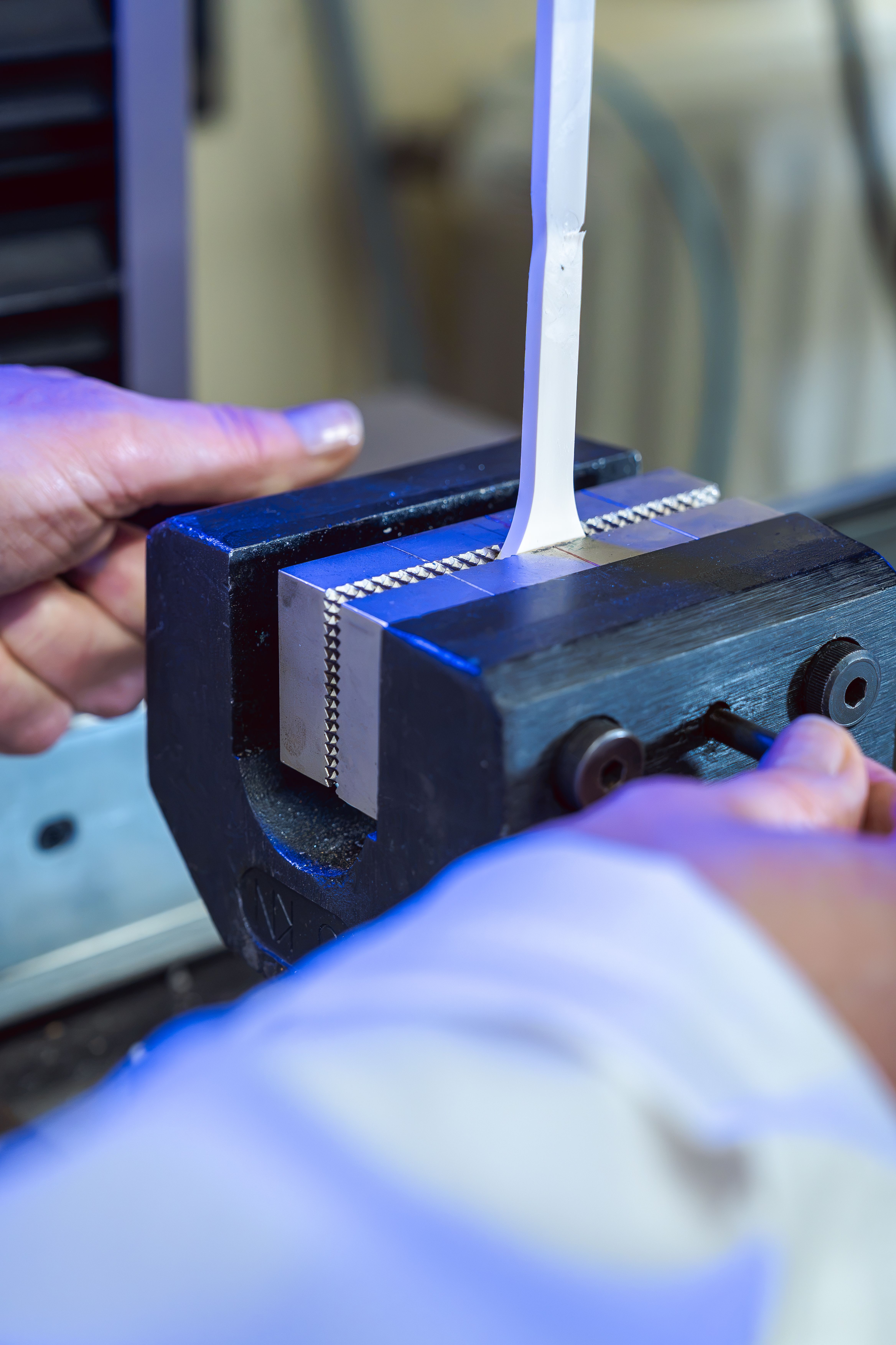 Mains préparant une machine avec de la matière première en train d’être étirée dans le laboratoire pour tester la résistance