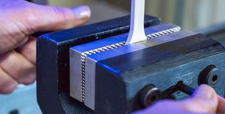 Mains préparant une machine avec de la matière première en train d’être étirée dans le laboratoire pour tester la résistance