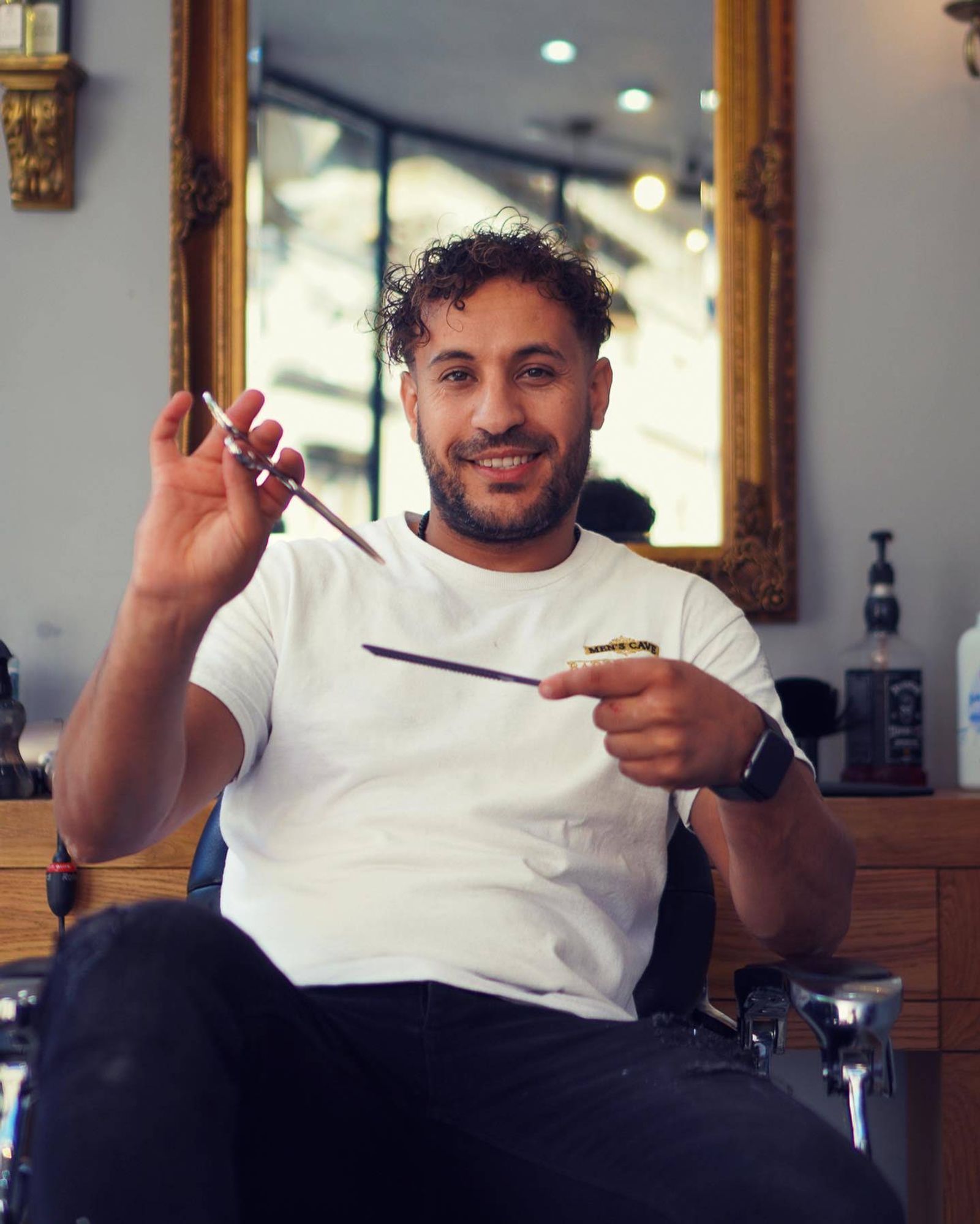 A Men’s Cave barber mid-haircut with scissors