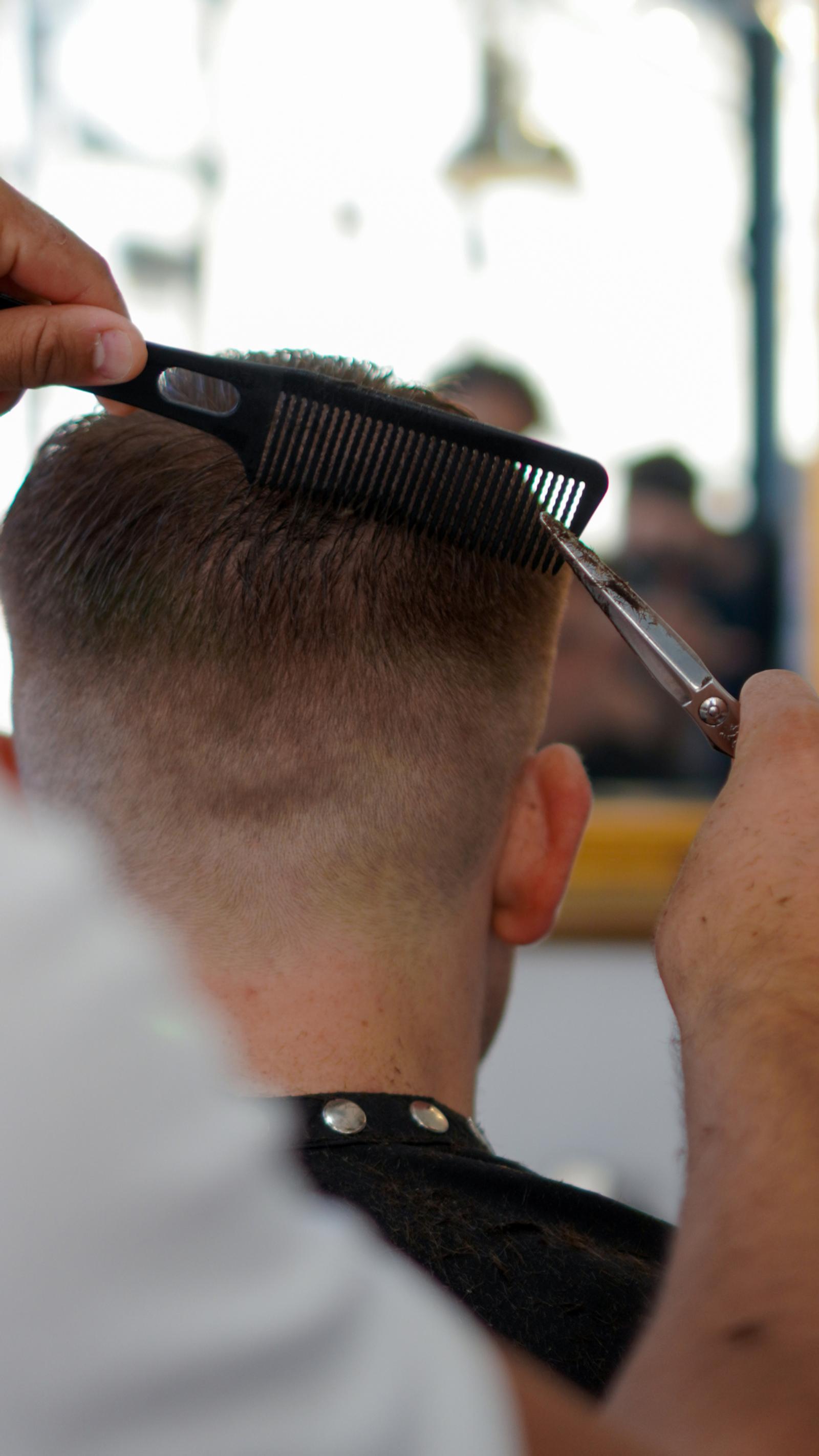 Barber cutting a tight skin fade with comb and scissors at Men’s Cave Barbers