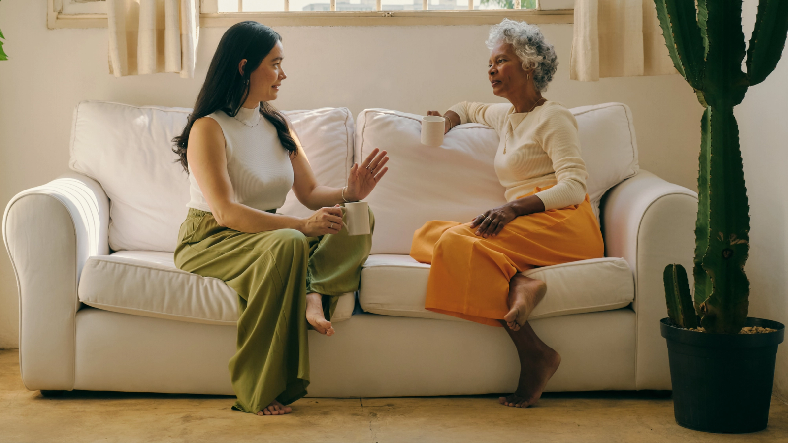 Two women relaxing on the couch and chatting over a cup of chicory
