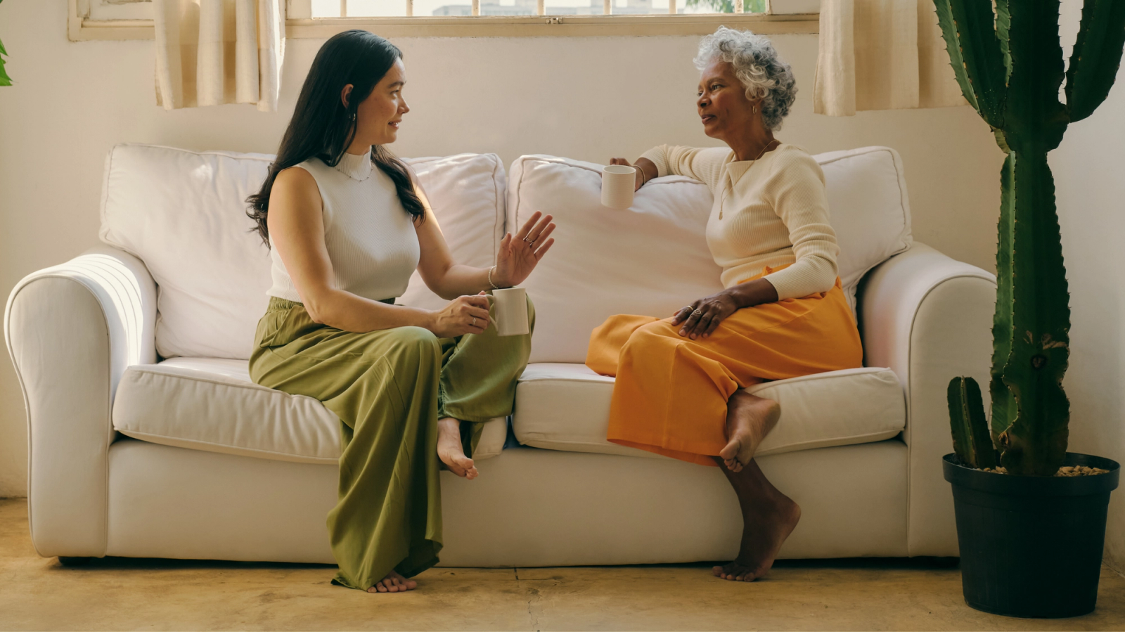 Two women relaxing on the couch and chatting over a cup of chicory