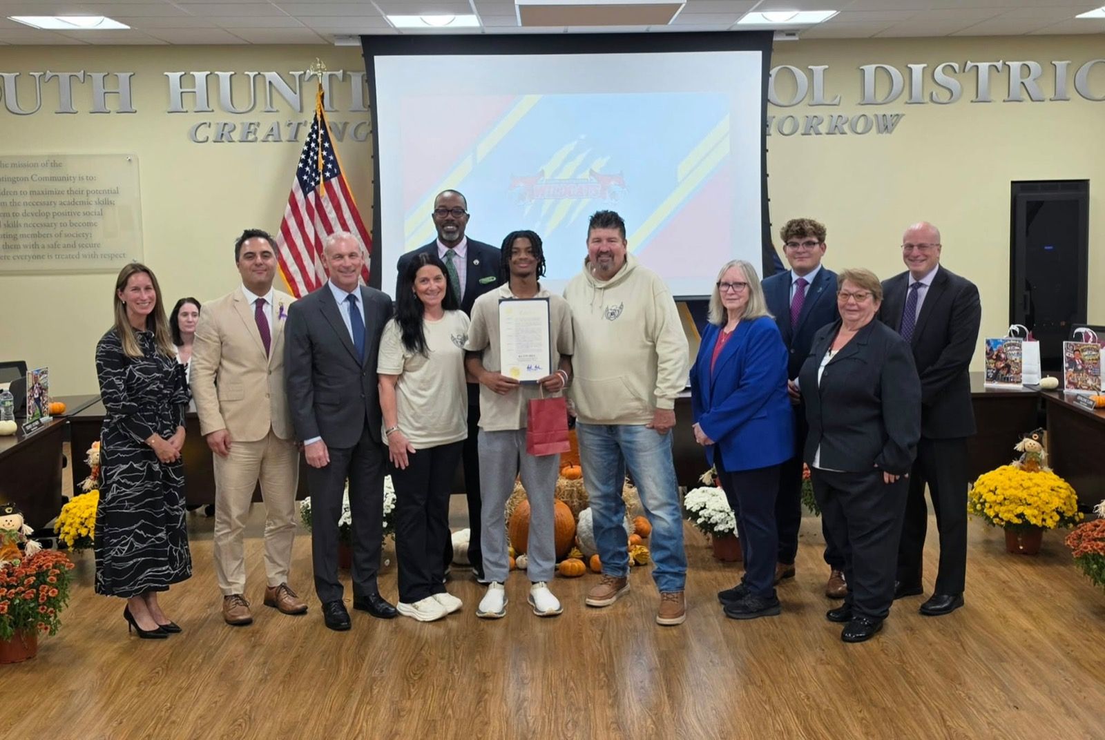 Keith Hill holding his proclamation at the South Huntington Board of Education meeting, with Assemblyman Steve Stern, the Kraese family and school staff