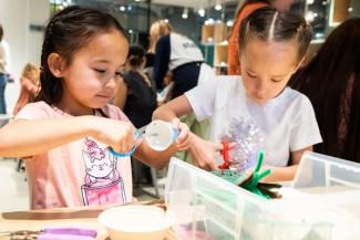 Two young girls cut paper cups with scissors.