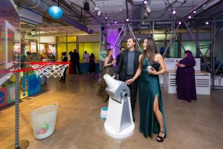 A woman in formal wear playing with National Children's Museum's Bernoulli's Hoops exhibit