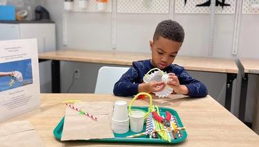 A child sitting at a table and working with a variety of art materials