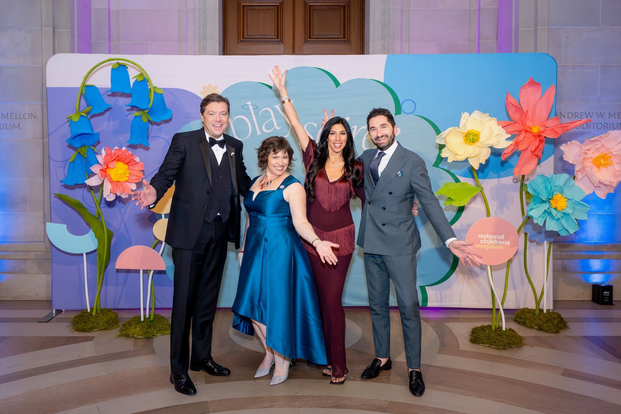 National Children's Museum President and CEO, Kiryn Hoffman, with event co-chairs John Drew, Sepe Zuccari, and Jason Zuccari, posing in front of the event photo backdrop