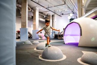 A child is leaping across the Museum floor's large half-circle stepping stones