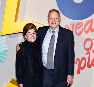Two people posing in front of the National Children's Museum Dreamers Gala step and repeat.