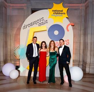 People posing in front of the National Children's Museum Dreamers Gala step and repeat.