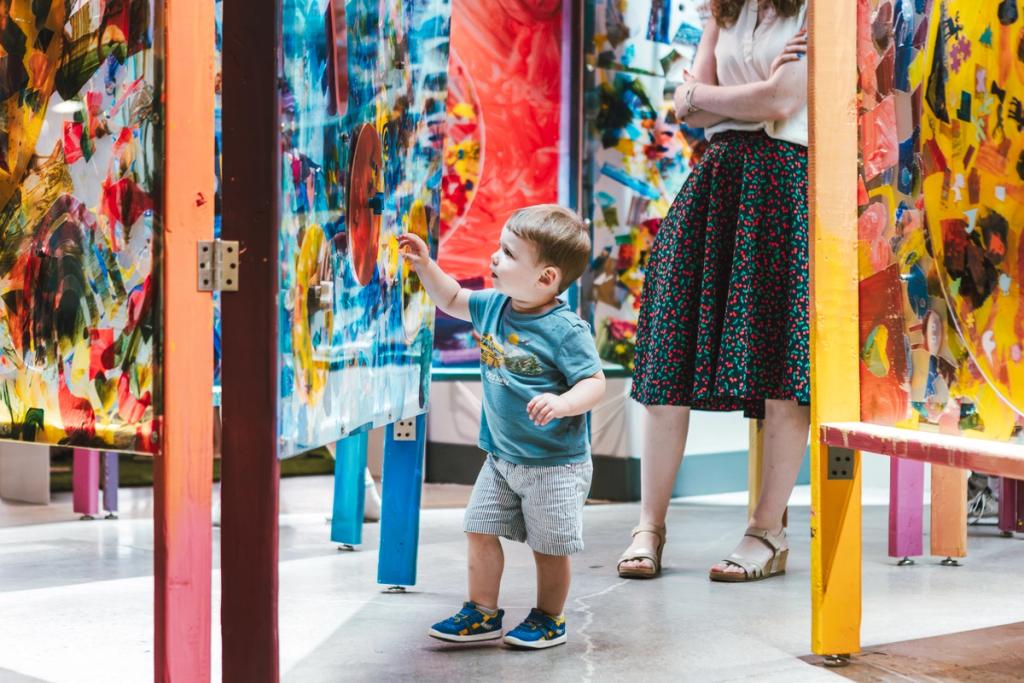 young boy touches wall of painted art