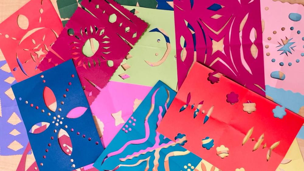 colorful paper papel picado pieces on top of each other on a table