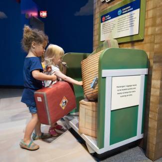 two little girls loading pretend luggage onto a cart